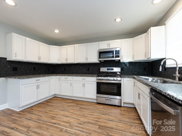 kitchen featuring appliances with stainless steel finishes, light hardwood / wood-style floors, white cabinetry, and sink