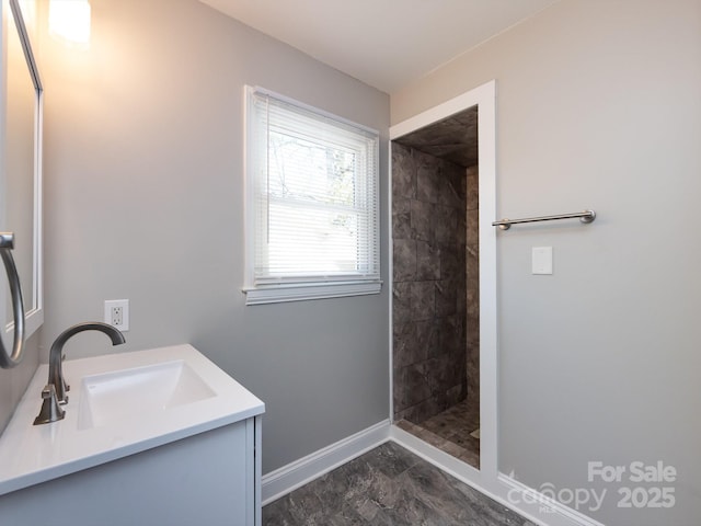 bathroom with a tile shower and vanity