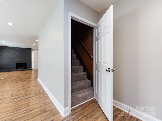 staircase with hardwood / wood-style floors and a large fireplace