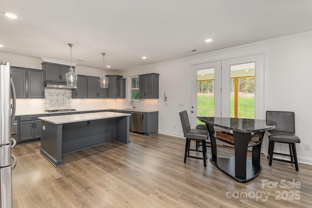 kitchen with a center island, a breakfast bar area, gray cabinets, decorative light fixtures, and stainless steel appliances