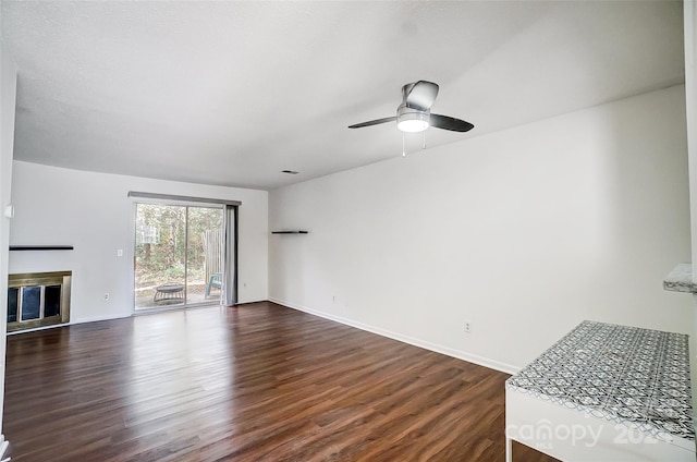 unfurnished living room featuring ceiling fan and dark wood-type flooring