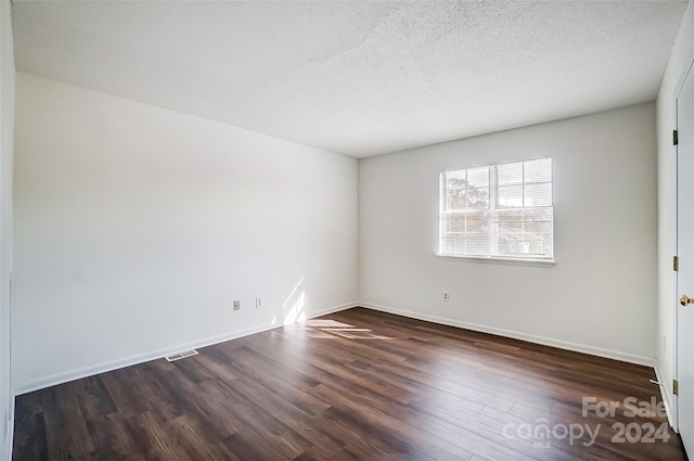 empty room featuring dark hardwood / wood-style floors and a textured ceiling