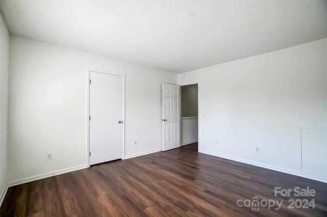 unfurnished bedroom featuring a textured ceiling and dark hardwood / wood-style floors