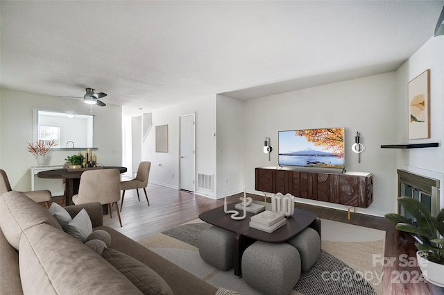 living room featuring wood-type flooring and ceiling fan