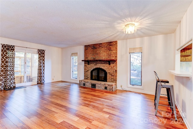 unfurnished living room with a wealth of natural light, light hardwood / wood-style floors, and a brick fireplace