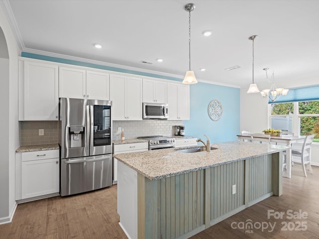 kitchen with appliances with stainless steel finishes, white cabinetry, sink, a kitchen island with sink, and light stone countertops