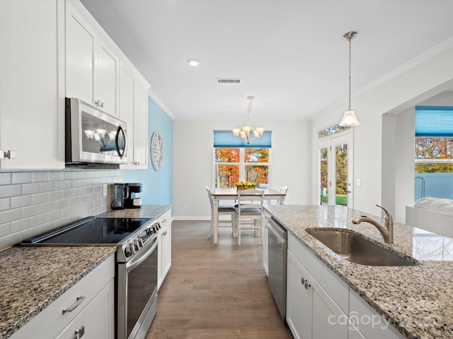 kitchen featuring pendant lighting, appliances with stainless steel finishes, sink, and white cabinets