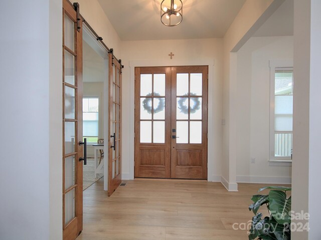 doorway with french doors, a barn door, and light hardwood / wood-style flooring