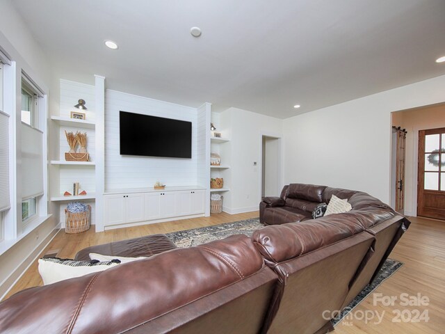 living room featuring built in features and light wood-type flooring