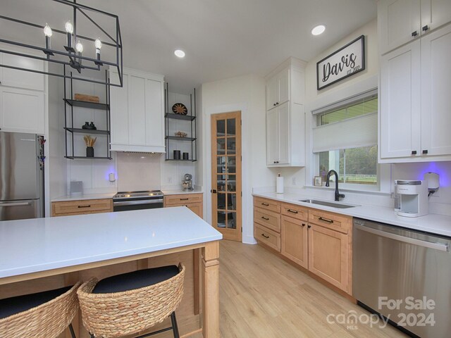 kitchen with stainless steel appliances, sink, light brown cabinets, light hardwood / wood-style floors, and white cabinetry