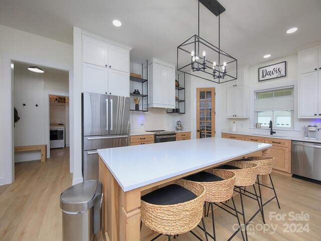 kitchen featuring white cabinets, a kitchen breakfast bar, light hardwood / wood-style flooring, appliances with stainless steel finishes, and a kitchen island