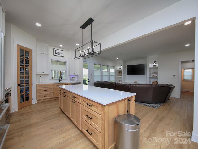 kitchen with pendant lighting, a center island, white cabinets, and light hardwood / wood-style flooring