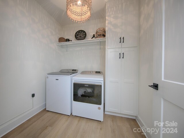 laundry room featuring cabinets, light wood-type flooring, a notable chandelier, and washing machine and clothes dryer