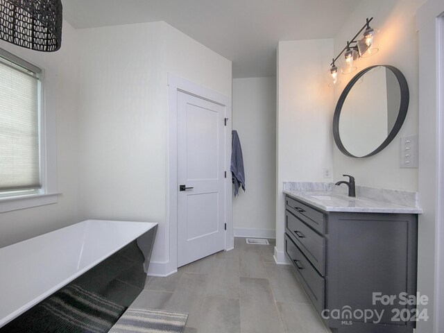 bathroom featuring tile patterned flooring, a washtub, and vanity