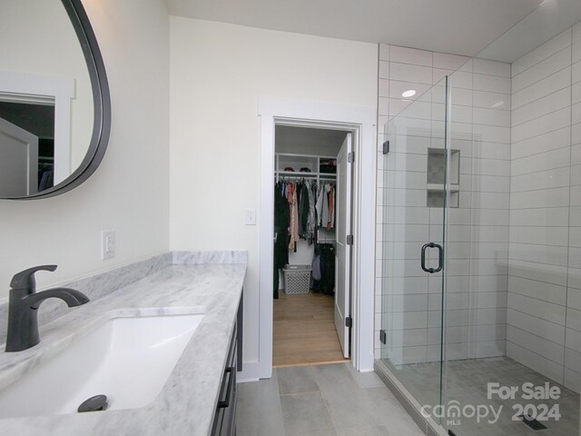 bathroom with hardwood / wood-style floors, vanity, and a shower with door