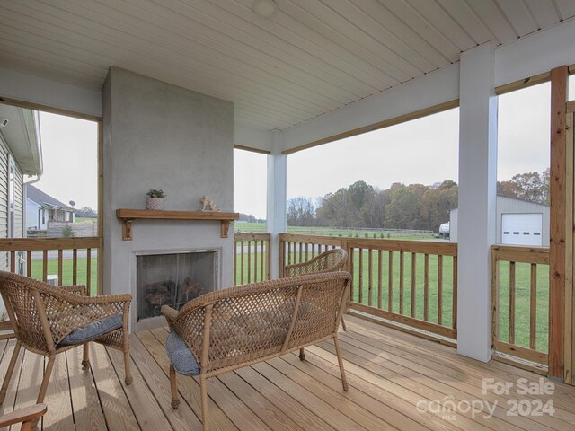 wooden terrace with a fireplace and a lawn