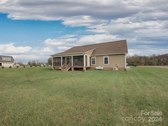 rear view of house with a yard and a sunroom