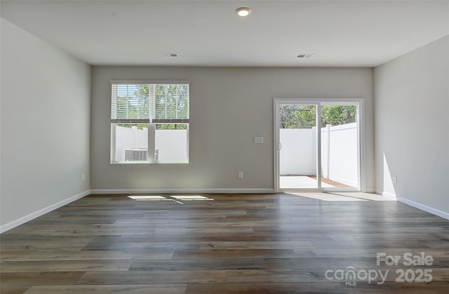 empty room with dark hardwood / wood-style flooring and a healthy amount of sunlight