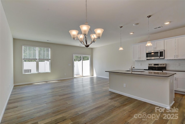 kitchen with white cabinetry, hanging light fixtures, stainless steel appliances, tasteful backsplash, and a center island with sink