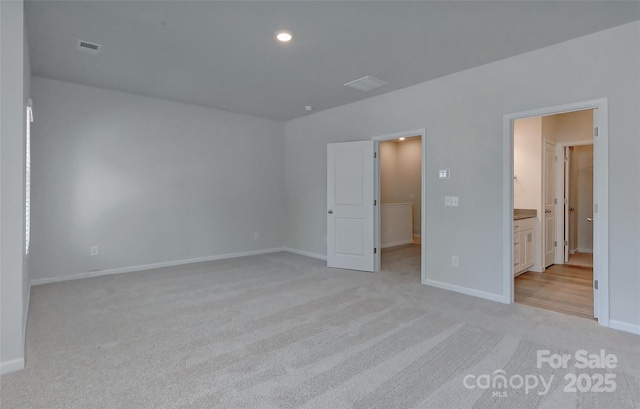 unfurnished bedroom with ensuite bathroom and light colored carpet