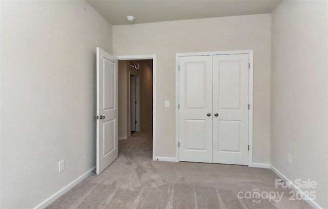 unfurnished bedroom featuring light carpet and a closet