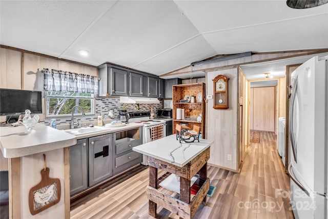 kitchen featuring light wood-type flooring, sink, white refrigerator, gray cabinets, and lofted ceiling