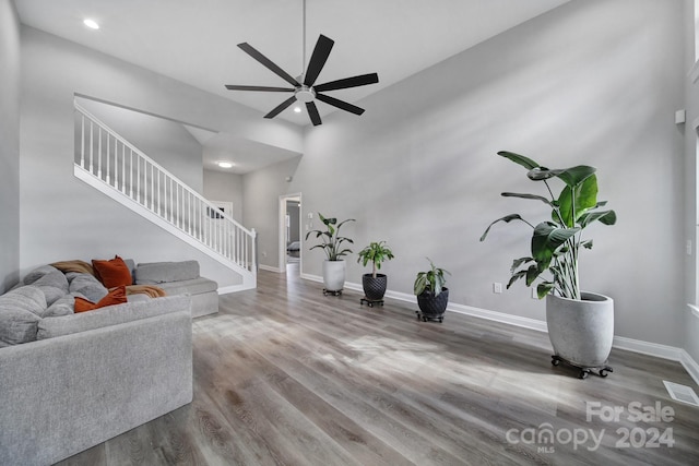 living room featuring a high ceiling, hardwood / wood-style flooring, and ceiling fan