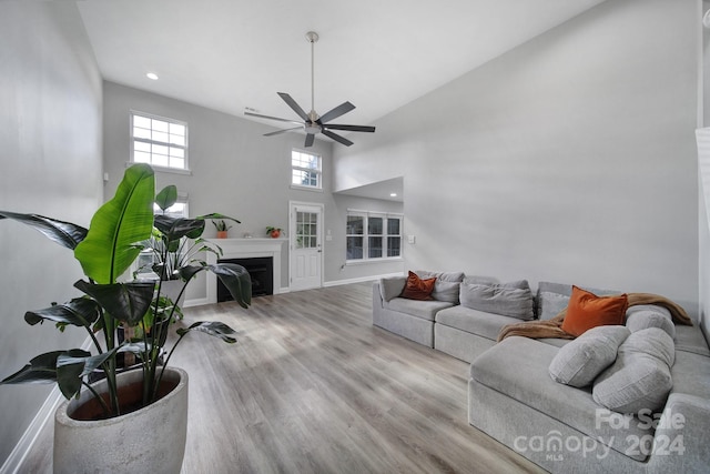 living room with light wood-type flooring, high vaulted ceiling, and ceiling fan