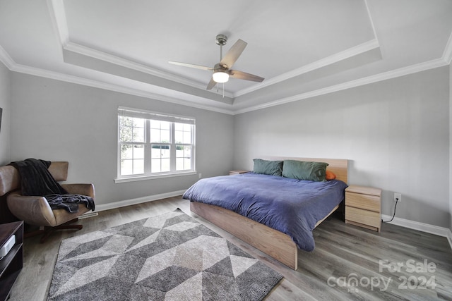 bedroom with hardwood / wood-style flooring, ceiling fan, and a tray ceiling