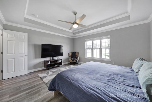 bedroom with a tray ceiling, ceiling fan, hardwood / wood-style floors, and crown molding