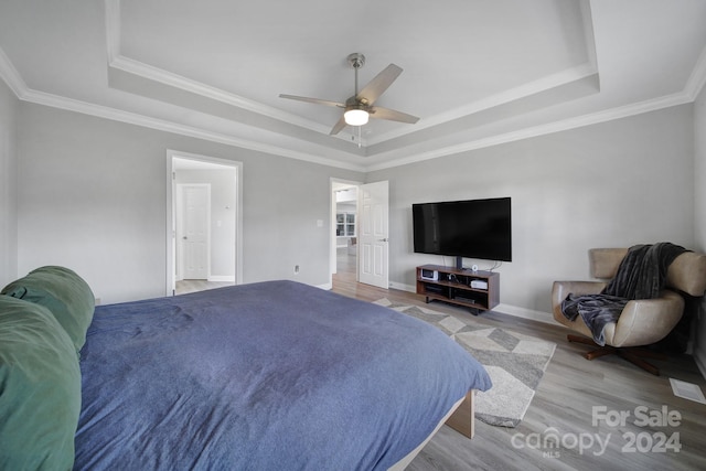 bedroom with a tray ceiling, ceiling fan, light hardwood / wood-style flooring, and ornamental molding