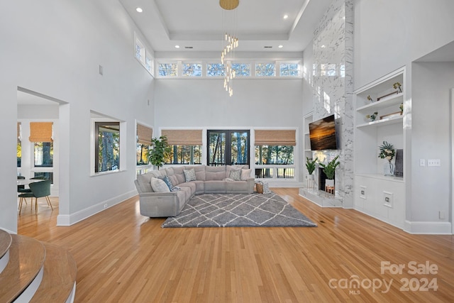 unfurnished living room featuring a high ceiling, a large fireplace, light hardwood / wood-style flooring, and a healthy amount of sunlight