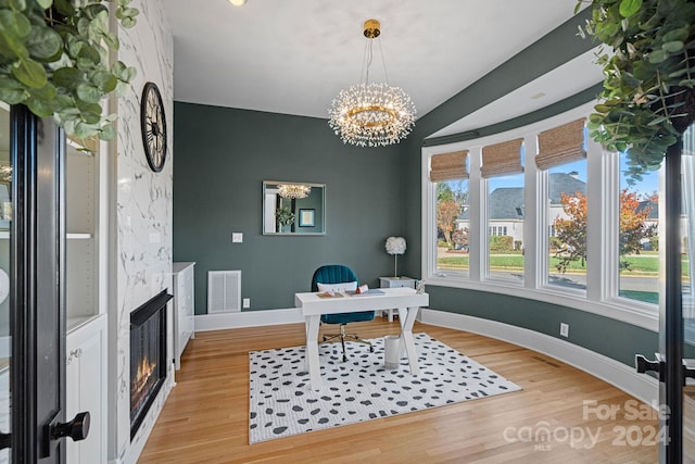 home office with light wood-type flooring, a large fireplace, and a notable chandelier