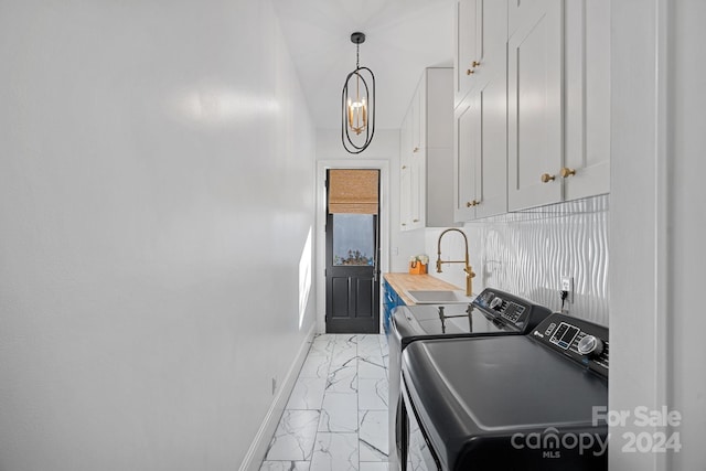 washroom featuring cabinets, sink, an inviting chandelier, and washing machine and clothes dryer