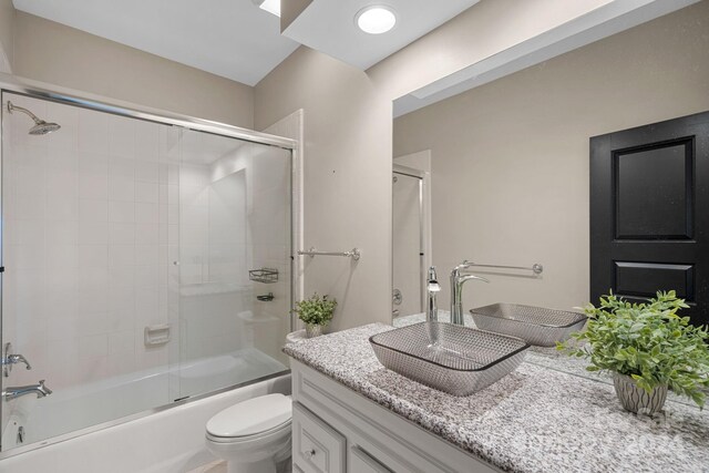 full bathroom featuring vanity, toilet, and enclosed tub / shower combo