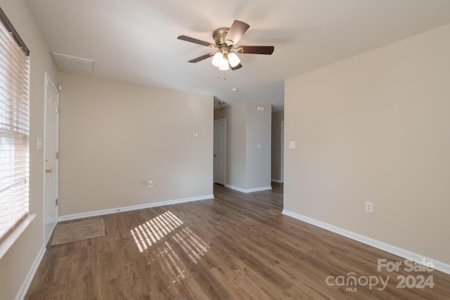 unfurnished room with plenty of natural light, ceiling fan, and dark wood-type flooring