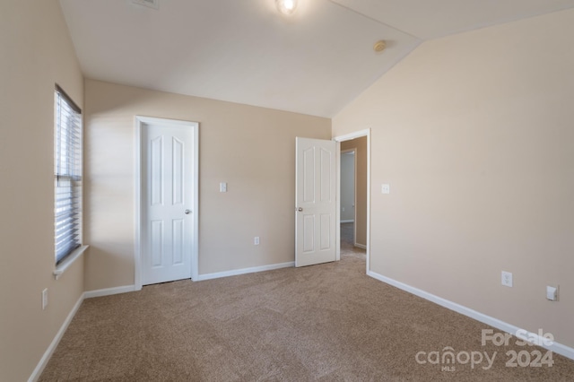 unfurnished bedroom featuring lofted ceiling and carpet floors