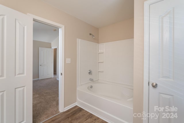 bathroom with hardwood / wood-style floors and washtub / shower combination