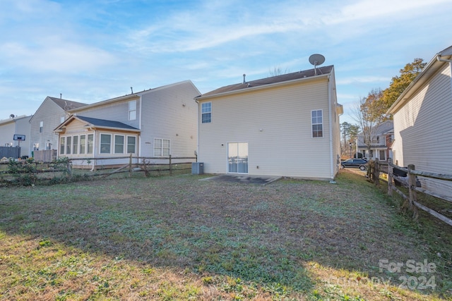 rear view of property featuring a lawn and cooling unit