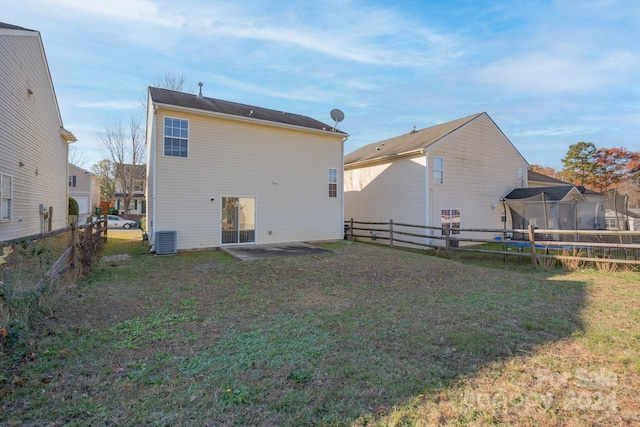 rear view of property featuring a lawn and central air condition unit