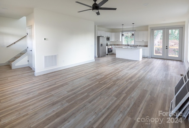 unfurnished living room featuring french doors, light hardwood / wood-style floors, and ceiling fan