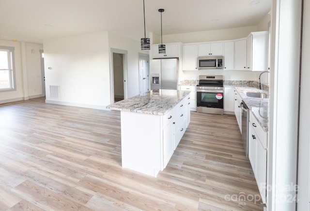 kitchen with stainless steel appliances, sink, decorative light fixtures, a center island, and white cabinetry