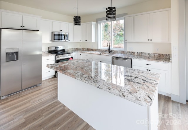 kitchen featuring white cabinetry, sink, hanging light fixtures, stainless steel appliances, and a kitchen island