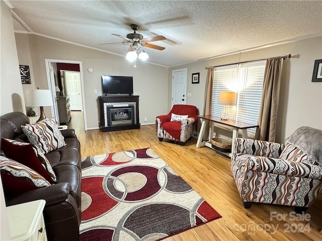 living room featuring ceiling fan, crown molding, lofted ceiling, a textured ceiling, and light wood-type flooring