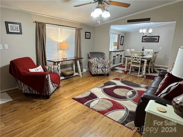 living room with ceiling fan with notable chandelier, a healthy amount of sunlight, light wood-type flooring, and crown molding