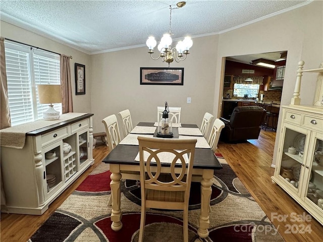 dining room featuring a textured ceiling, crown molding, a notable chandelier, and hardwood / wood-style flooring