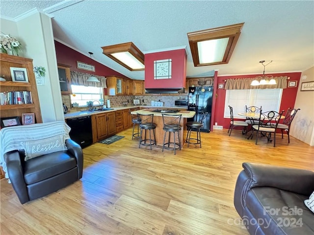 kitchen featuring a kitchen breakfast bar, an inviting chandelier, light hardwood / wood-style flooring, and black appliances