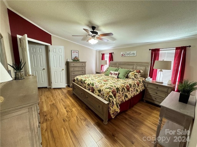 bedroom with a textured ceiling, ceiling fan, crown molding, hardwood / wood-style floors, and lofted ceiling