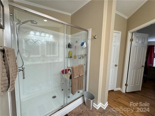 bathroom featuring hardwood / wood-style flooring, crown molding, a textured ceiling, and walk in shower