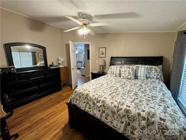 bedroom with wood-type flooring, a textured ceiling, ceiling fan, and crown molding